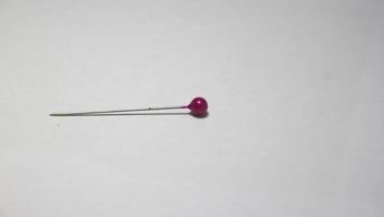 Single one straight pin for clothing and fashion sewing themed purposes on simple background. Horizontal side view. photo