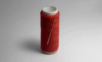 Single one Tailoring and sewing equipments, red orange brown thread roll and needle. Thin and simple, easy and quick to use. Photo on white plain background, side light layout.