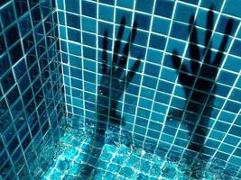 sombras de manos en los mosaicos de la piscina foto