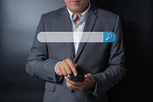 cierra a un hombre de negocios empujando, tocando en un smartphone con una barra de búsqueda virtual en un fondo negro y gris