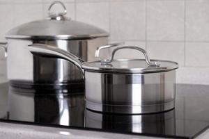 Ladle and large saucepan stand on modern stove with a glass-ceramic hob photo