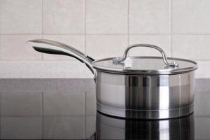 Stainless steel ladle sits on modern stove with glass-ceramic hob. photo