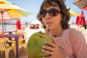 dama en la playa disfrutando de un coco helado en un día soleado foto