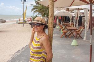 Lady at the beach in Combuco, Brazil, leaning against wooden pole photo