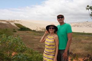 Couple standing in front of the Sand Dunes that are in Combuco, Brazil in the State of Ceara photo