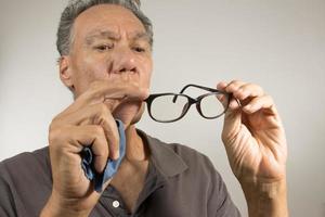 Mature man cleaning and checking his eye glasses to see if there clean photo