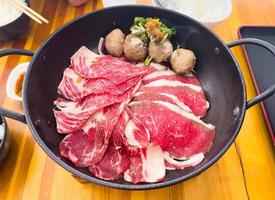 Fresh beef slice serving in the pan with meatball and some vegetable before fill hot soup photo