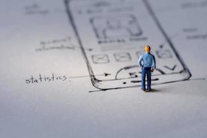 User Experience Concept. present by Miniature Figure of UX UI Designer standing on Paper of Interface Design Sketch photo