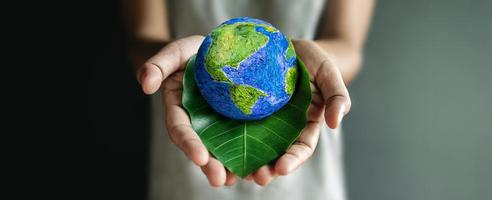 World Earth Day Concept. Green Energy, Renewable and Sustainable Resources. Environmental and Ecology Care. Hand Embracing Green Leaf and Handmade Globe photo