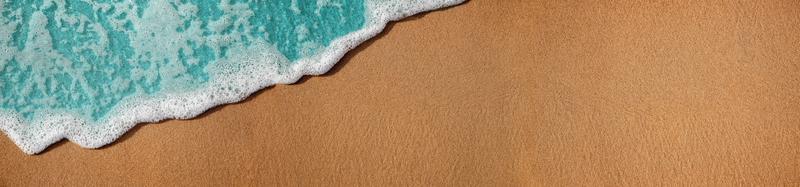 Empty Sand Beach and Soft Blue Wave on Summer Sunny Day. Natural Texture Background. Wide and Long Size for Copy Space. Top View. Focus on Sand photo