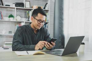 Man using smartphone after working with laptop on table, businessman using mobile phone to search or social media or shopping online or stock or crypto currency. Smart phone conversation conferrence. photo