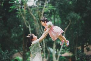 Asia disfruta de la feliz madre mamá sosteniendo a su hija y pasándola bien en el parque de otoño. concepto de familia. padre e hijo hija. familia feliz. foto