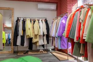 coloridos vestidos, chaquetas, pantalones y otras prendas de mujer en perchas en una tienda minorista. el concepto de moda y compras. boutique de ropa de mujer.