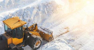limpieza de nieve tractor despeja el camino después de fuertes nevadas. un gran tractor naranja quita la nieve de la carretera y despeja la acera. limpieza de caminos en la ciudad de la nieve en invierno. foto