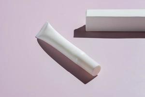 Eye cream package mockup. Unbranded plastic tube and paper box on pink background with harsh shadows. photo