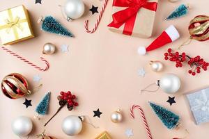 fondo de navidad con decoraciones, marco hecho de regalos, bastones de caramelo, bolas y árboles sobre fondo beige, puesta plana