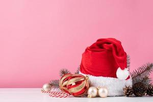 adornos navideños con sombrero de santa, bolas y pinos sobre fondo rosa, espacio para copiar foto