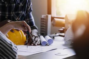 Construction engineer working at blueprint to build large commercial buildings in office. Engineering tools and construction concept. photo