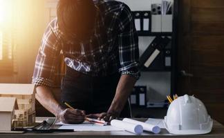Construction engineer working at blueprint to build large commercial buildings in office. Engineering tools and construction concept. photo