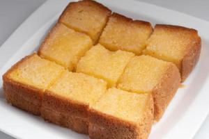 Toasted bread slices topped with sweetened condensed milk in a white plate. photo