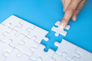 White jigsaw in the hands, The correct solution. Teamwork, Solving and completing the task. Last piece of jigsaw puzzle. Assembling jigsaw puzzle pieces. photo