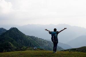Young traveler woman with stylish backpack  looking forward at amazing mountains view. Enjoying nature, relax, pleasure. photo