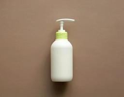 White corrugated bottle surface soap dispenser pump. Skin care Lotion. Bathing essential product. Shampoo bottle. Mock-up pump bottle of moisturizing lotion, soap, or sanitizer on beige background. photo