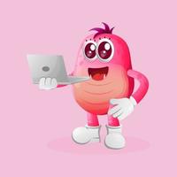 Cute pink monster working using a laptop vector