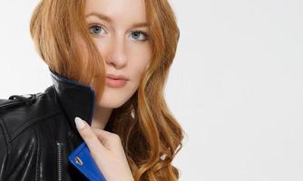 Woman beauty power. Close up of red haired girl face, leather jacket isolated on white background. Skin care, blue eyes and beautiful face. Copy space and selective focus. Redhead, no make up. Banner photo