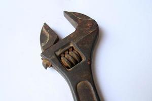 Close-up view of the head of an old rusty adjustable wrench on white background. Old rusty iron wrench for turning screws. Household and construction concept photo