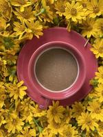 Red cup of coffee with yellow flowers , top view photo