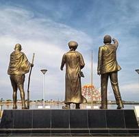 Makassar,Indonesia,31 Juni 2021-three people statue golden color overlooking the mosque in the middle of the sea with a sky blue background photo