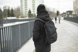 chico vestido de negro en la calle. mochila negra de hombre. europeo en la ciudad. foto