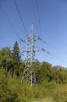Electric transmission line in forest. Steel tower with wires. High-voltage infrastructure. photo