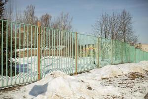 Fence around school in winter. Green fence in city. Private territory. photo