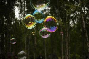 Soap bubbles fly through air. Balloons on background of forest. Soap solution for holiday.