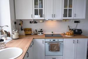 White cozy kitchen in Scandi loft style. Home interior, dining room design, oven, hob, table, kitchen furniture photo