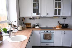 cocina blanca y acogedora en estilo loft scandi. interior de la casa, diseño de comedor, horno, vitrocerámica, mesa, muebles de cocina foto