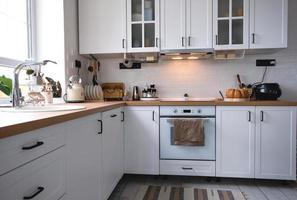 White cozy kitchen in Scandi loft style. Home interior, dining room design, oven, hob, table, kitchen furniture photo