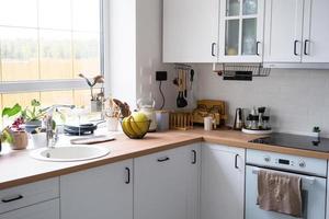 cocina blanca y acogedora en estilo loft scandi. interior de la casa, diseño de comedor, horno, vitrocerámica, mesa, muebles de cocina foto