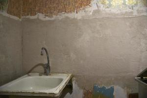 An old iron kitchen sink with a faucet in the old kitchen. Renovation in the kitchen and fresh plaster. Sink with a sanitary siphon. photo