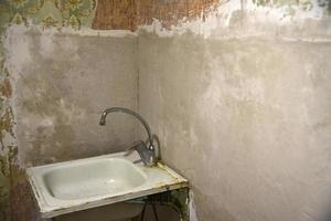 An old iron kitchen sink with a faucet in the old kitchen. Renovation in the kitchen and fresh plaster. Sink with a sanitary siphon. photo