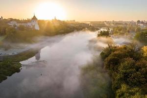 earlier foggy morning and aerial panoramic view on medieval castle and promenade overlooking the old city and historic buildings near wide river photo