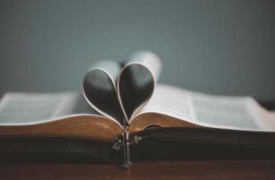 abra el libro de la santa biblia espiritual con la página en forma de corazón doblada en el centro y el collar cruzado. foto