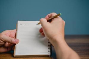 2023 Happy New Year Resolution Goal List, Hand with pen writing on notebook with copy space, plan listing of new year goals and resolutions setting. Change and determination concept.. photo