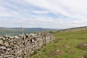 Muro de piedra apilada en seco con las colinas de los valles de Yorkshire, Reino Unido, al fondo foto