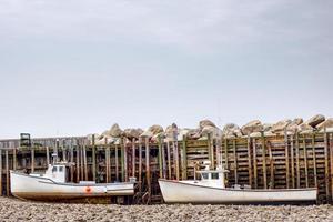 two fishing boats sitting on the bottom at low tide in the bay of fundy photo