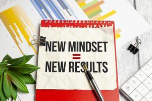 New Mindset - New Results on red notebook and wooden background with charts photo