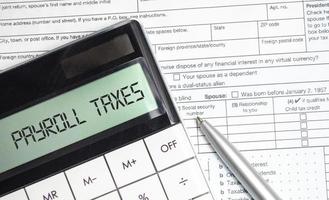 payroll taxes words on calculator display and tax forms