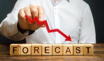 Man holds red arrow down over word Forecast. A budget shortage, recession economy, unprofitable company. Prediction of profit fall, value of assets and market conditions. reduction income and earnings photo
